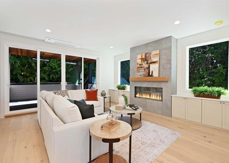 Living room at 5620 6th Avenue NW with a white sectional, linear fireplace, large windows and sliding doors to a covered deck